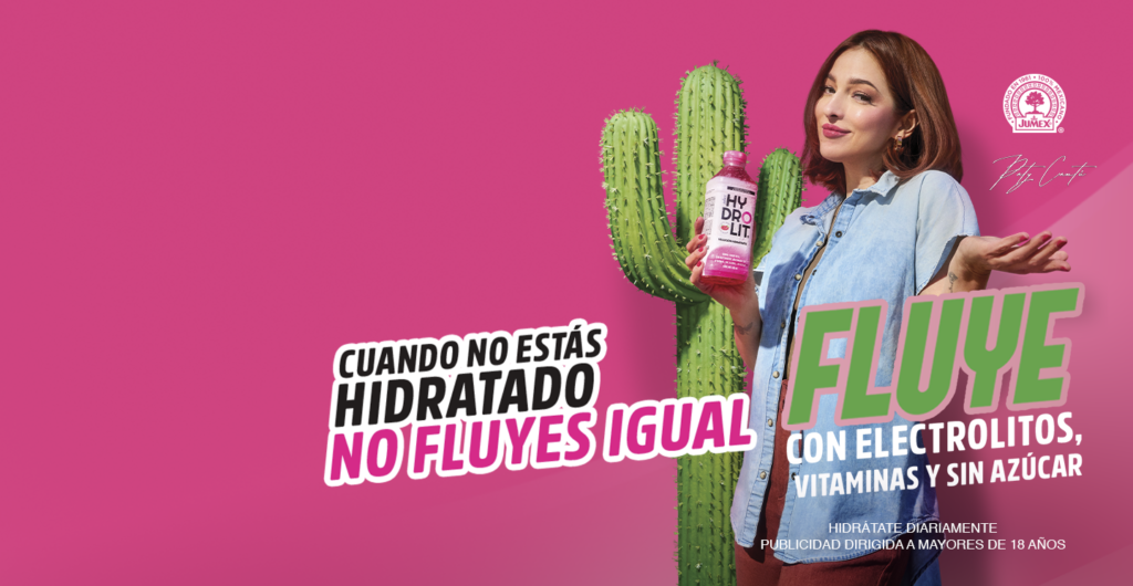 Pele Cruz sosteniendo una botella rosa de Jumex Hydrolit con electrolitos y vitaminas en un fondo fucsia